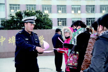 交警在學(xué)校門口向家長(zhǎng)發(fā)放校車安全宣傳單(資料片)。