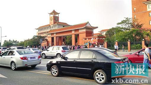 學校門口的路段停滿前來接送孩子的車輛,不少家長在校門口等候。