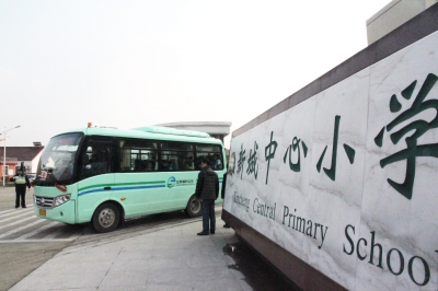 鎮(zhèn)村公交校車按順序駛出校園送學(xué)生回家。